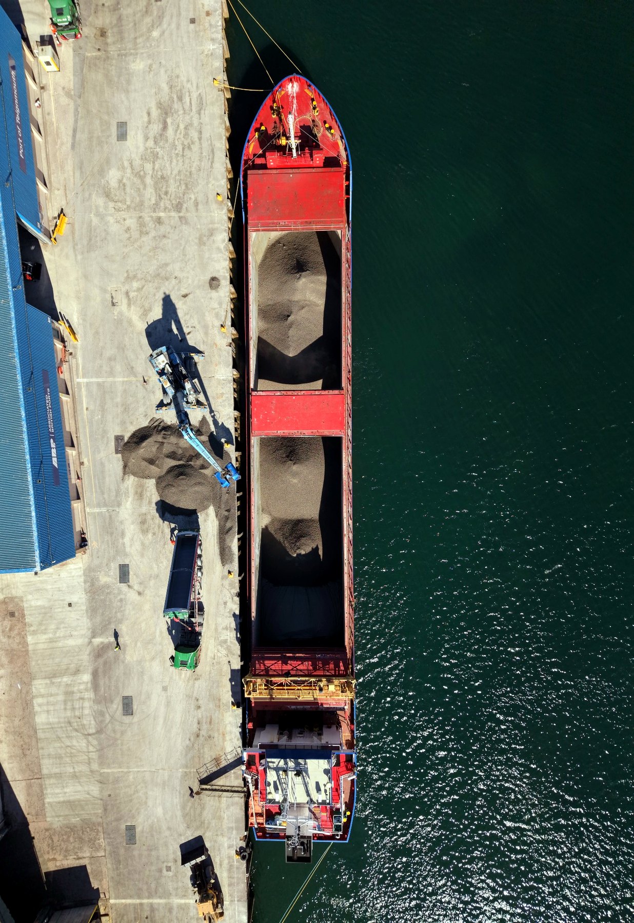Real drone top-down view of port operations, quayside access and material handling context